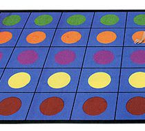 A kid sitting on a classroom rug with individual seating spaces with rows of multi colored circles
