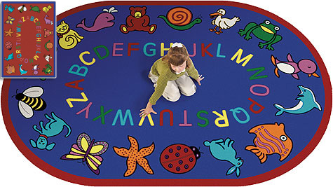 a girl kneeling on a rug with letters. This rug is blue with the alphabet around the center and whimsical animals around the edge.