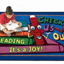 A child sitting on a kids rug reading a book.