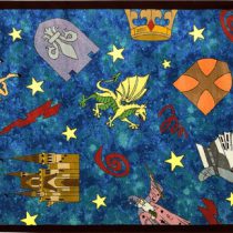 A blue children's rug with wizards, unicorns, dragons and a castle.
