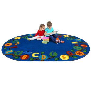 Two children sitting and reading on a blue oval educational kids rug with the alphabet in upper case on leaves of a tree.